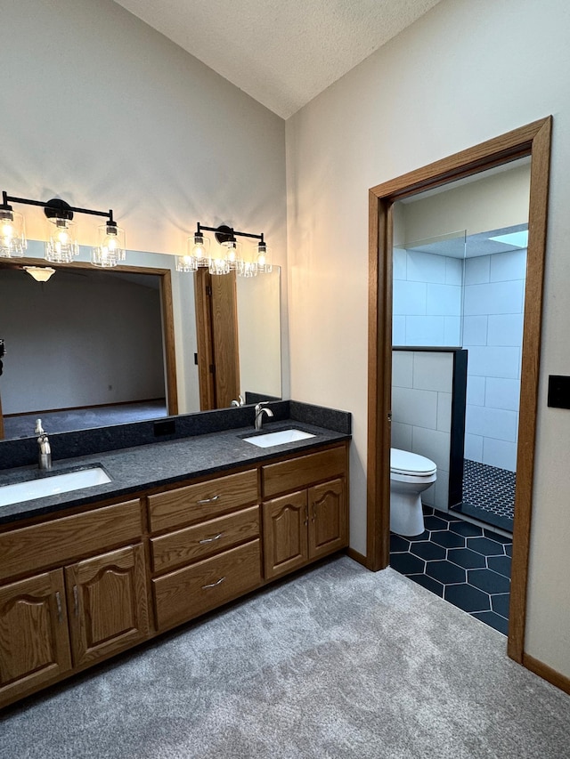 full bath featuring toilet, a sink, double vanity, and a tile shower