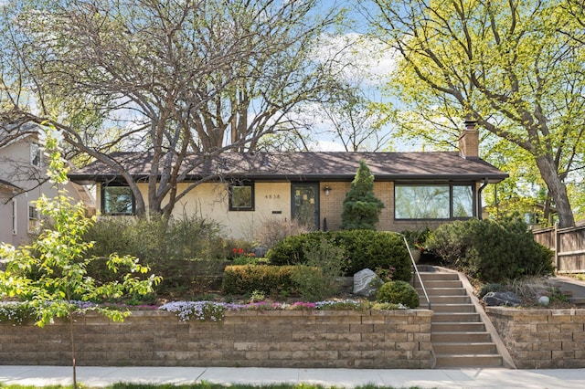 ranch-style house with fence, stairs, stucco siding, and a chimney