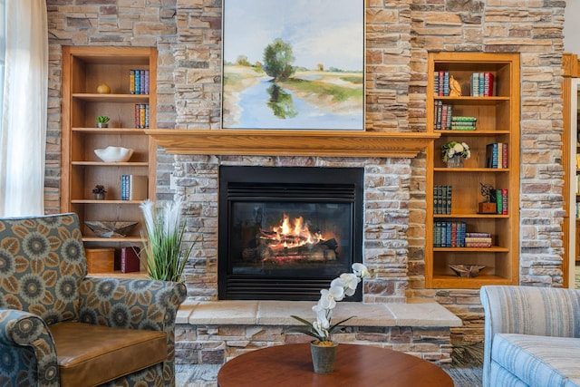living room featuring built in features and a stone fireplace