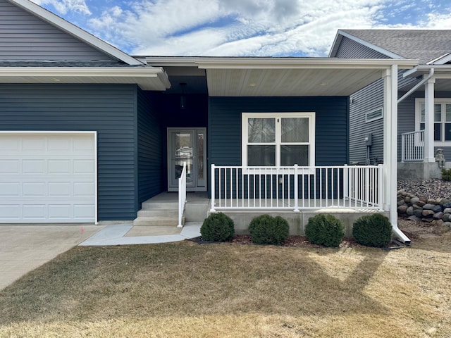 property entrance with driveway, covered porch, a garage, and a yard