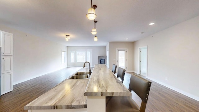 dining area with recessed lighting, a stone fireplace, baseboards, and dark wood finished floors
