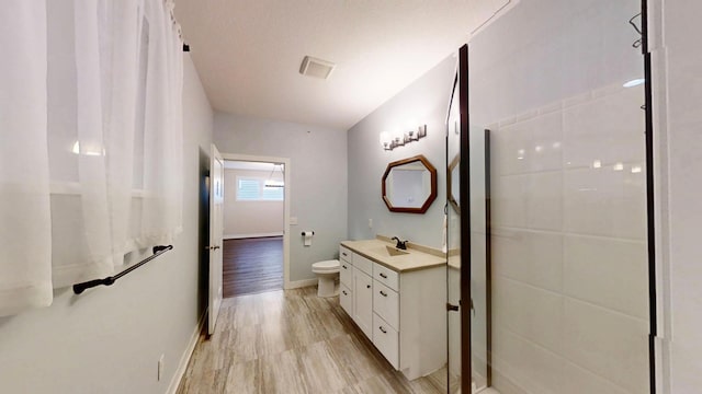 bathroom with baseboards, wood finished floors, toilet, and vanity