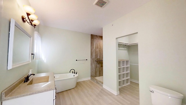 bathroom featuring a tile shower, toilet, vanity, visible vents, and a freestanding bath
