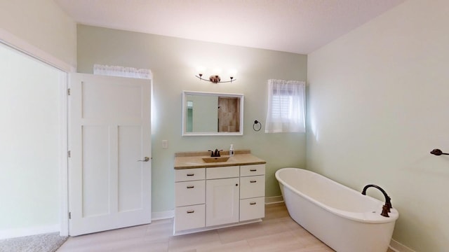 full bath with a soaking tub, vanity, and baseboards