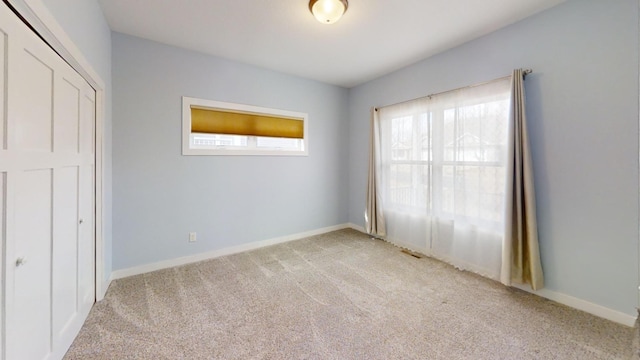 unfurnished bedroom featuring light carpet, baseboards, and a closet