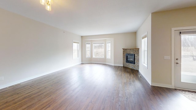 unfurnished living room featuring baseboards, a fireplace, visible vents, and dark wood-type flooring
