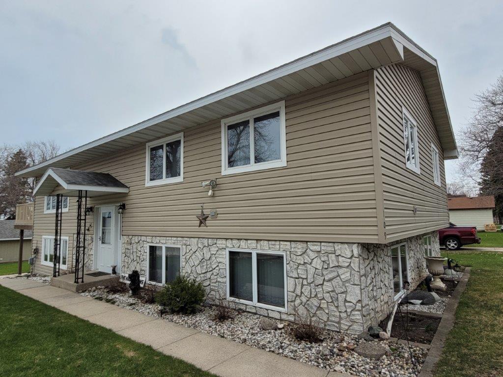 rear view of house with stone siding and a yard