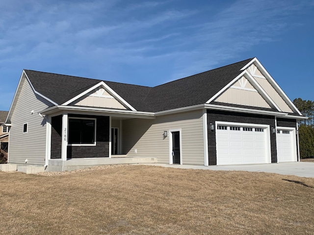 view of front of home featuring an attached garage, concrete driveway, a front lawn, board and batten siding, and stone siding