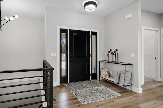 entryway featuring a chandelier, wood finished floors, and baseboards