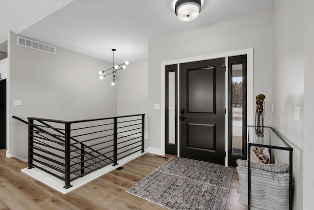 foyer featuring wood finished floors, a chandelier, and baseboards