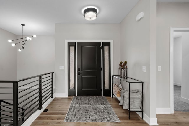 entryway featuring a chandelier, wood finished floors, and baseboards