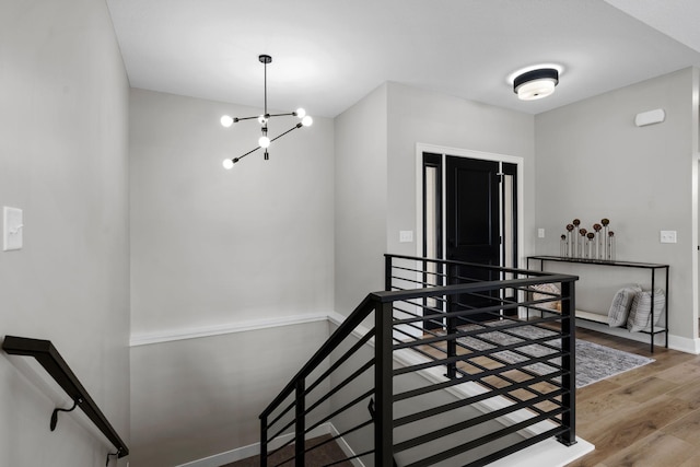 stairs featuring wood finished floors, a chandelier, and baseboards