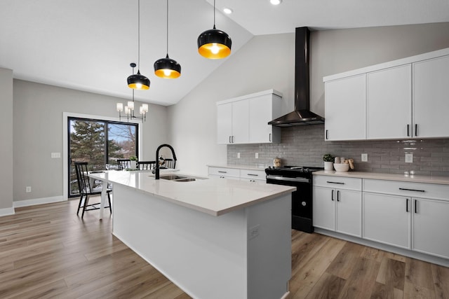 kitchen with a sink, black electric range oven, wall chimney range hood, tasteful backsplash, and light wood-type flooring