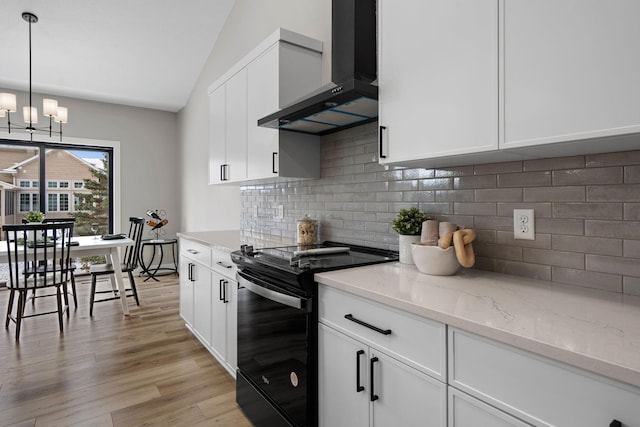 kitchen featuring black / electric stove, wall chimney range hood, vaulted ceiling, light wood-style flooring, and white cabinetry