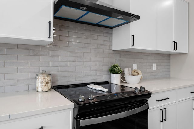 kitchen with black / electric stove, wall chimney range hood, white cabinets, tasteful backsplash, and light stone counters