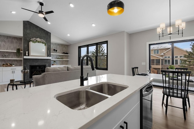 kitchen featuring a sink, dishwasher, lofted ceiling, healthy amount of natural light, and wood finished floors