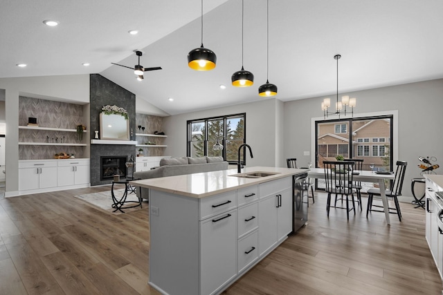 kitchen with a sink, lofted ceiling, black dishwasher, a tile fireplace, and wood finished floors