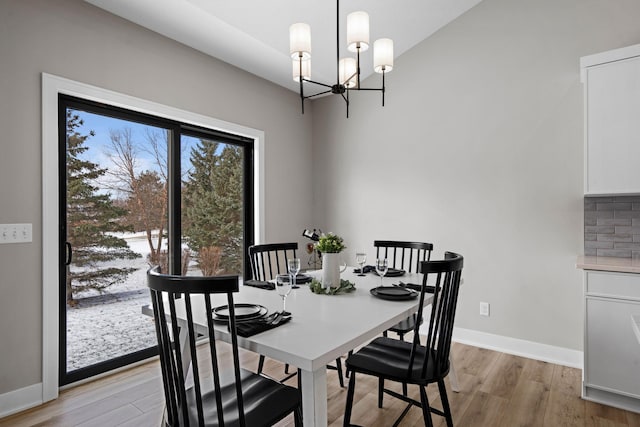 dining space with light wood-style flooring, a chandelier, and baseboards