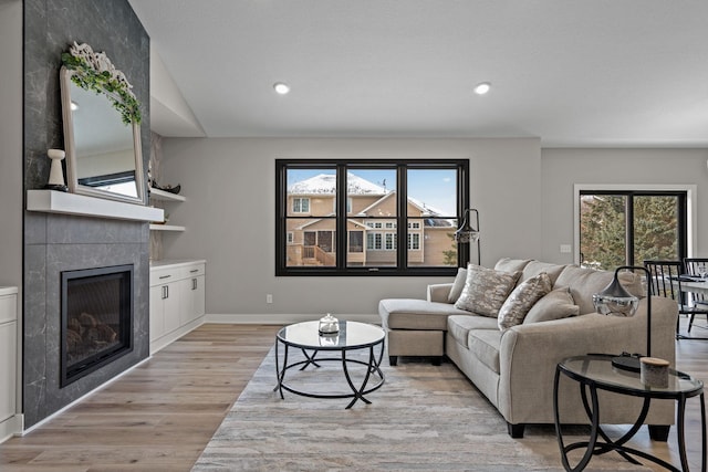 living area with light wood-style flooring, a fireplace, recessed lighting, baseboards, and vaulted ceiling