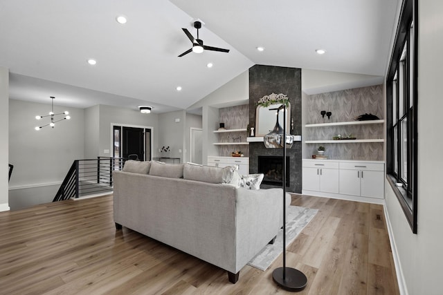 living area with a fireplace, light wood-style floors, ceiling fan, baseboards, and built in features