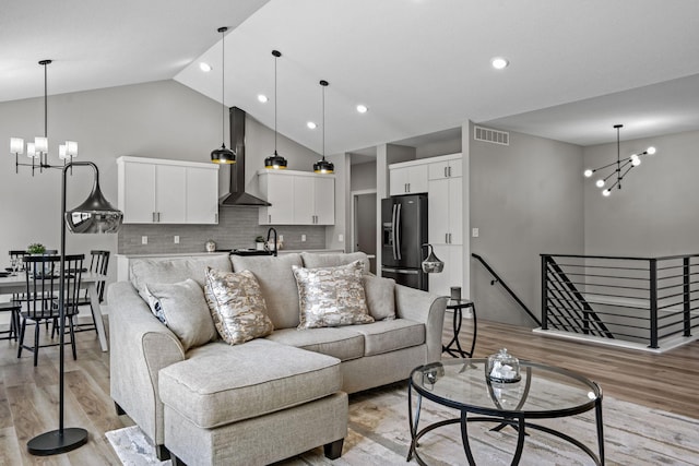 living room with a chandelier, light wood-style flooring, high vaulted ceiling, and recessed lighting