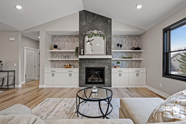 living room with lofted ceiling, a tiled fireplace, baseboards, recessed lighting, and light wood-style flooring