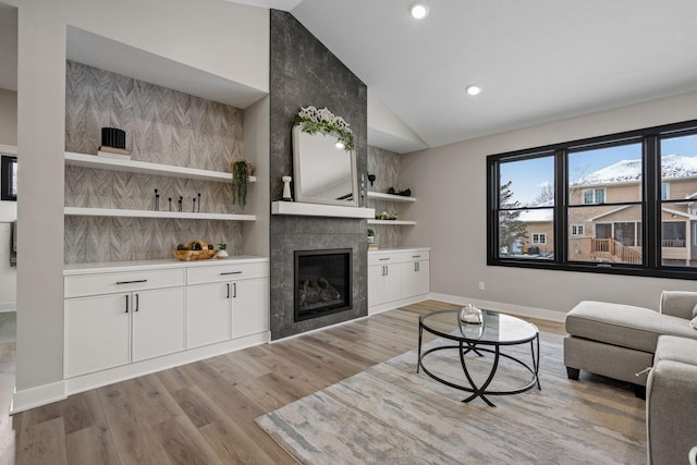 living room featuring vaulted ceiling, baseboards, a fireplace, wood finished floors, and recessed lighting