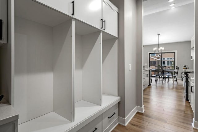mudroom featuring light wood-style flooring, baseboards, and a chandelier