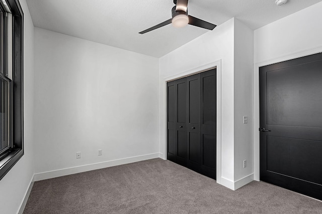 unfurnished bedroom featuring carpet floors, baseboards, a closet, and a ceiling fan