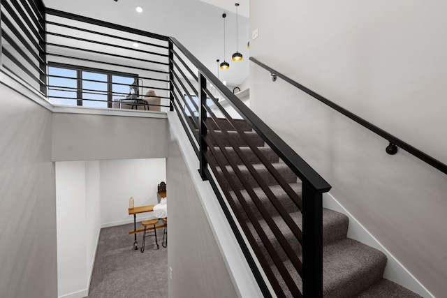 stairs featuring carpet floors, a high ceiling, and baseboards