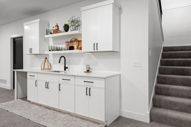 bar area with a sink, light colored carpet, stairway, and baseboards