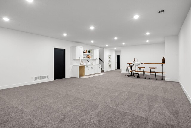 basement with recessed lighting, light colored carpet, baseboards, and bar area