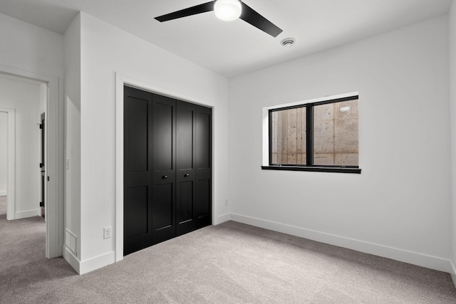unfurnished bedroom with carpet floors, baseboards, a closet, and ceiling fan