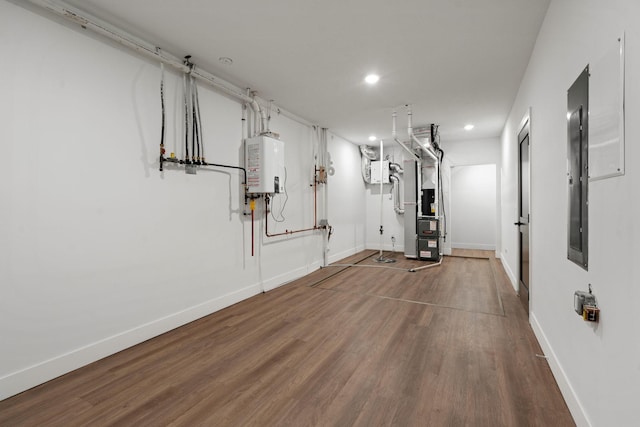 workout area featuring water heater, recessed lighting, wood finished floors, heating unit, and baseboards