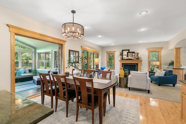 1301 Pondview Ln, Saint Joseph, MN 56374 - dining room featuring an inviting chandelier, plenty of natural light, a fireplace, and light wood-style flooring