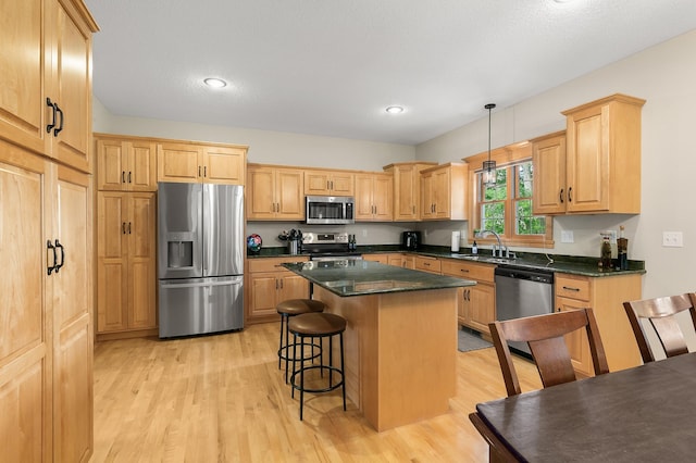 1301 Pondview Ln, Saint Joseph, MN 56374 - kitchen with appliances with stainless steel finishes, a sink, light wood-style floors, a center island, and a kitchen bar