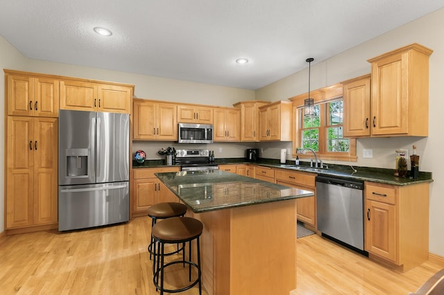 1301 Pondview Ln, Saint Joseph, MN 56374 - kitchen featuring a kitchen island, light wood-style floors, a kitchen breakfast bar, a sink, and appliances with stainless steel finishes