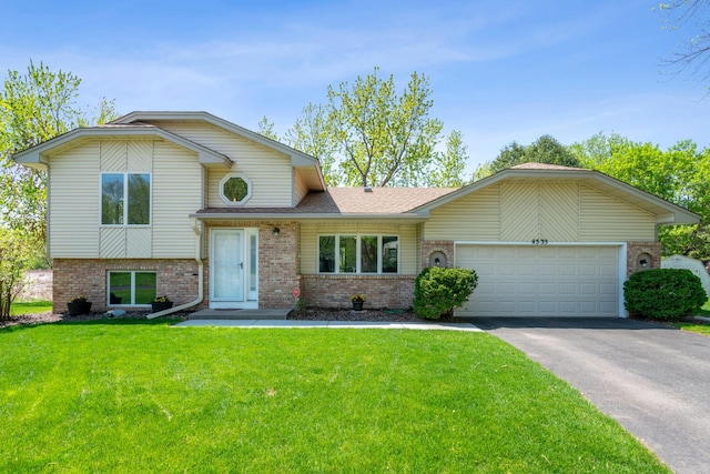 tri-level home featuring brick siding, driveway, an attached garage, and a front yard