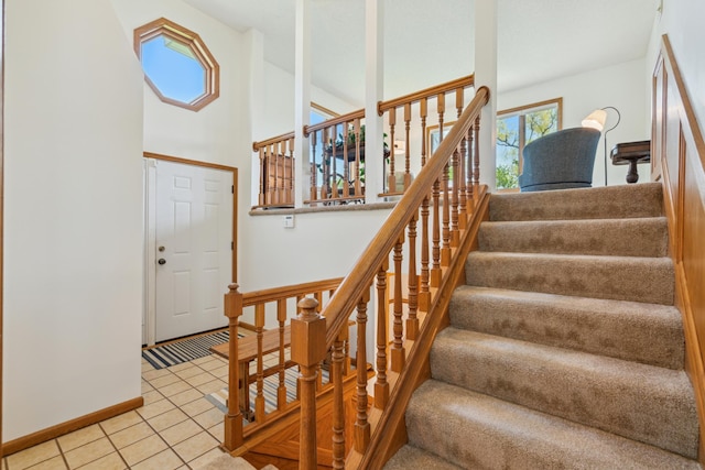 staircase featuring tile patterned floors, baseboards, and a high ceiling