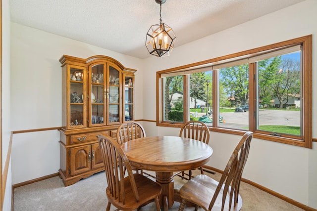 dining area featuring light carpet, baseboards, a textured ceiling, and a chandelier