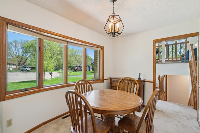 dining room with light colored carpet, healthy amount of natural light, a chandelier, a textured ceiling, and baseboards