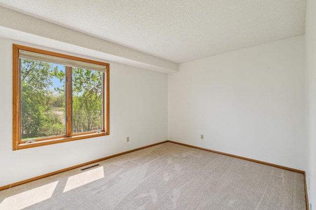 empty room with light carpet, baseboards, and a textured ceiling