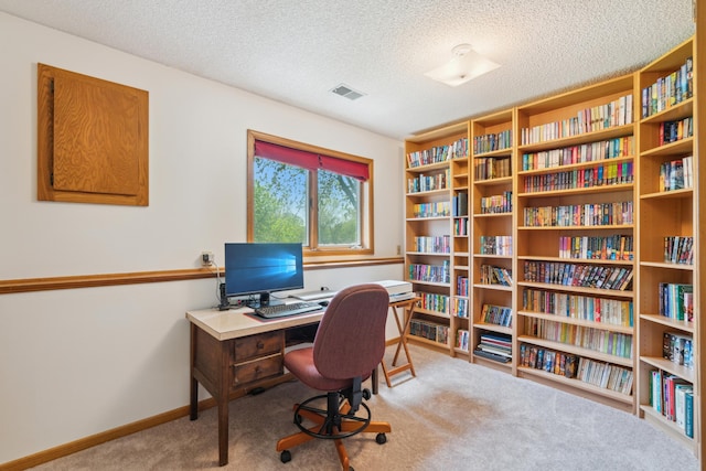 office with carpet flooring, baseboards, bookshelves, and a textured ceiling