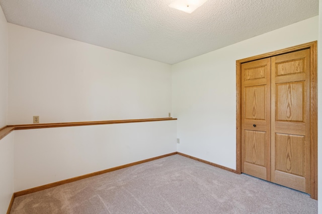 unfurnished room featuring carpet flooring, a textured ceiling, and baseboards
