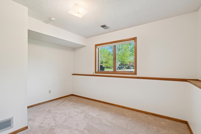 spare room featuring carpet, baseboards, and a textured ceiling