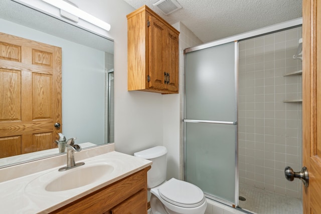 bathroom featuring a shower stall, toilet, a textured ceiling, and vanity