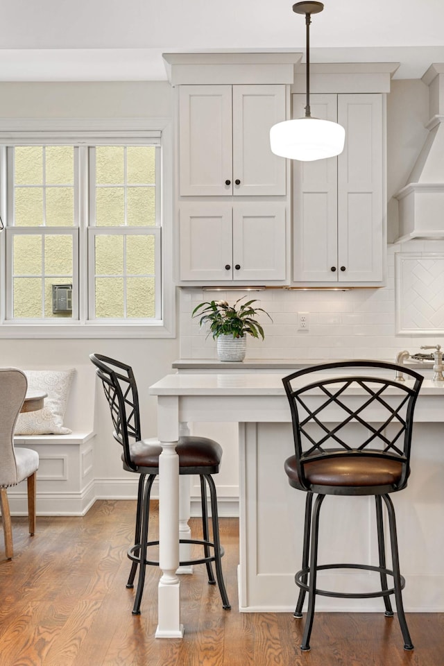 kitchen with wood finished floors, pendant lighting, a breakfast bar, and decorative backsplash