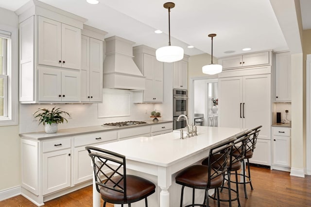 kitchen with a breakfast bar, dark wood-style floors, custom range hood, and appliances with stainless steel finishes
