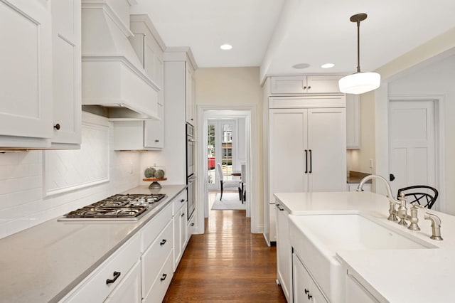 kitchen with white cabinetry, tasteful backsplash, dark wood-type flooring, appliances with stainless steel finishes, and custom exhaust hood