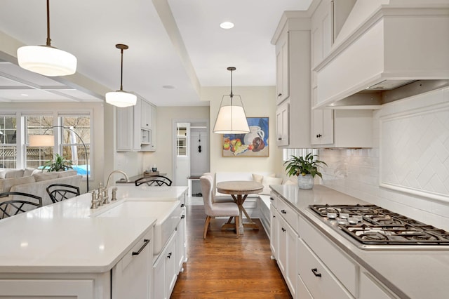 kitchen featuring light countertops, backsplash, premium range hood, dark wood-style floors, and stainless steel gas stovetop